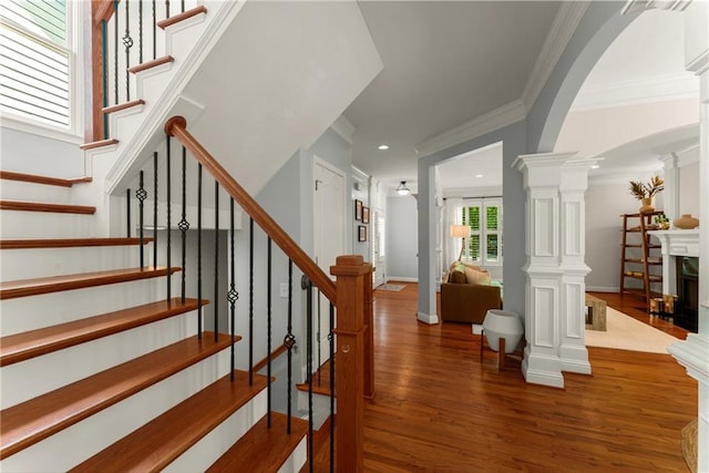 1560 Gilstrap Ln NW, Atlanta, GA 30318 - staircase with wood finished floors, arched walkways, crown molding, decorative columns, and recessed lighting