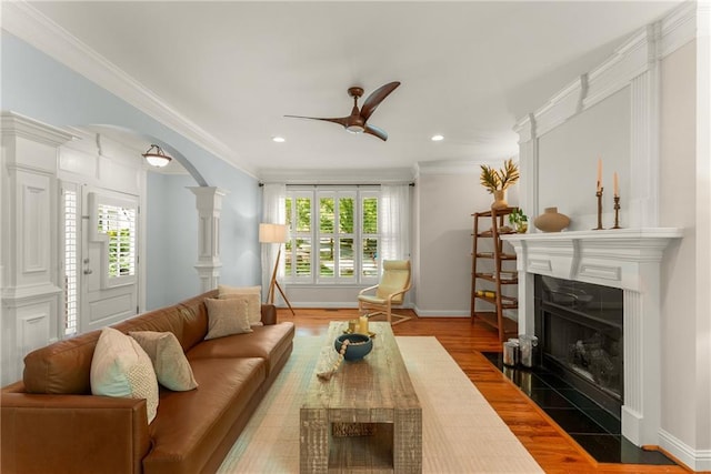 1560 Gilstrap Ln NW, Atlanta, GA 30318 - living area with a fireplace with flush hearth, a ceiling fan, wood finished floors, ornamental molding, and arched walkways