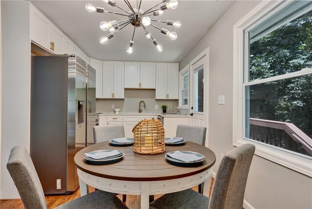 dining area with an inviting chandelier, sink, and light hardwood / wood-style floors