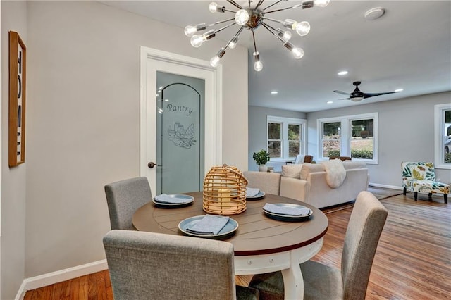 dining space featuring recessed lighting, a notable chandelier, baseboards, and wood finished floors