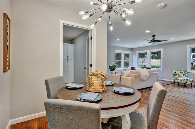 dining space with recessed lighting, a notable chandelier, baseboards, and wood finished floors