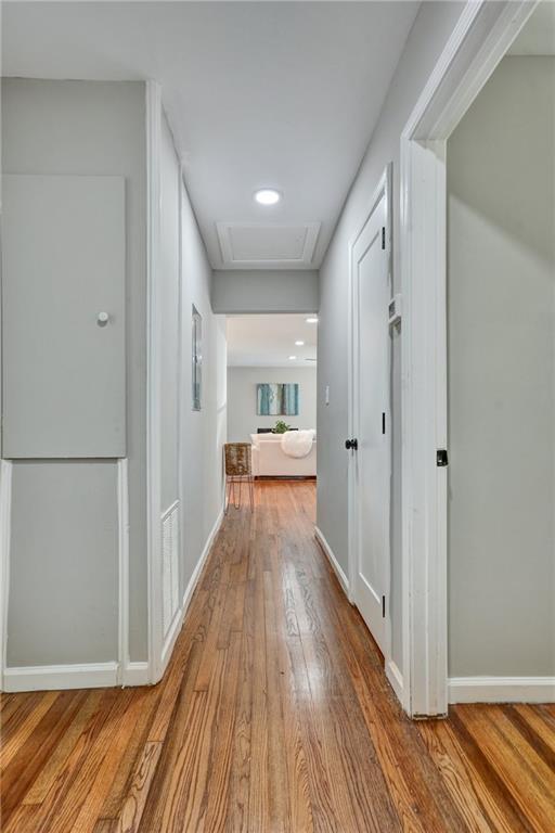 corridor with attic access, baseboards, and wood finished floors