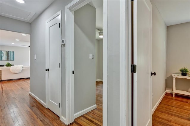 hall with recessed lighting, wood finished floors, attic access, and baseboards