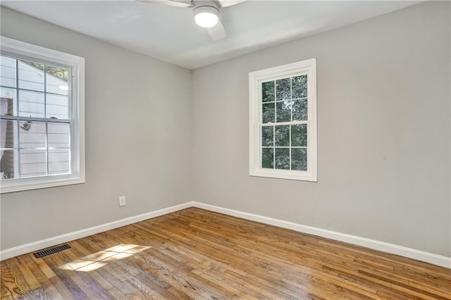 spare room featuring ceiling fan, light wood-style floors, visible vents, and baseboards