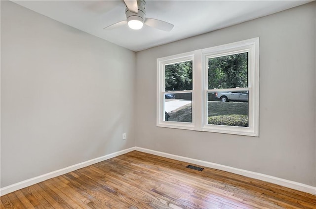 empty room with ceiling fan, hardwood / wood-style floors, and plenty of natural light