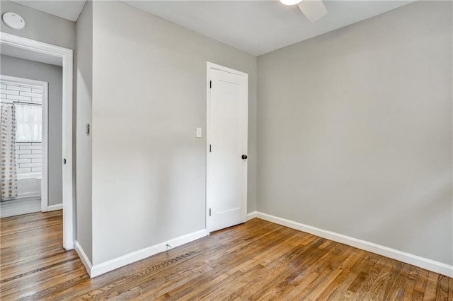 unfurnished room with wood finished floors, a ceiling fan, and baseboards