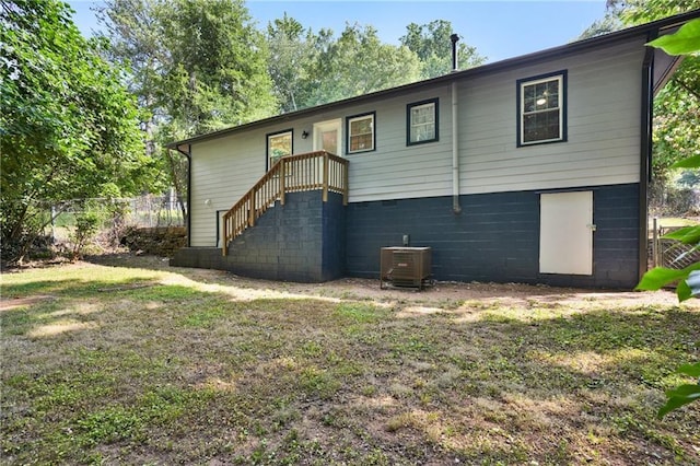 rear view of house with a lawn, fence, and cooling unit