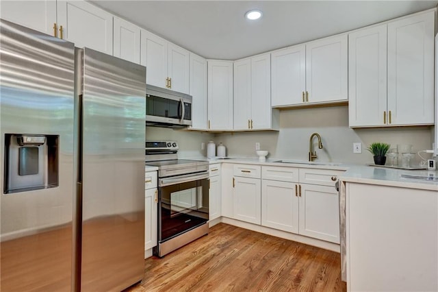 kitchen featuring white cabinetry, light wood-type flooring, appliances with stainless steel finishes, and sink