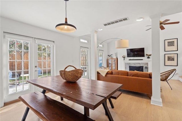 dining area featuring french doors, a wealth of natural light, visible vents, a premium fireplace, and light wood-type flooring