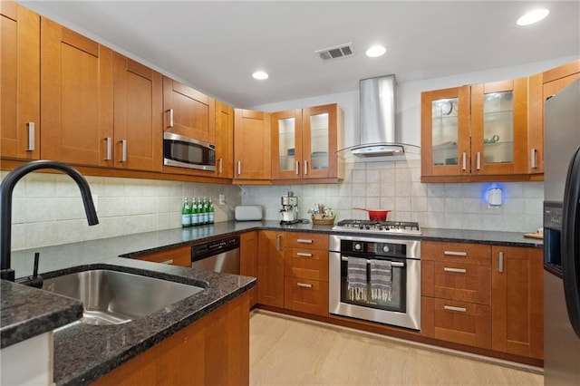 kitchen featuring wall chimney exhaust hood, glass insert cabinets, stainless steel appliances, and a sink