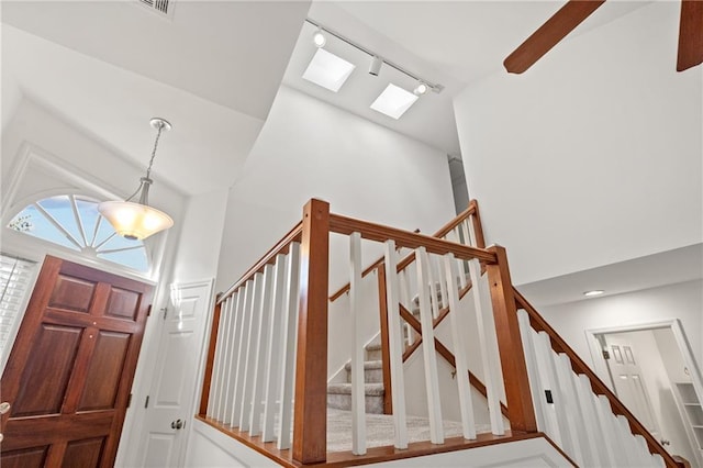 entryway featuring high vaulted ceiling, a skylight, stairway, and track lighting