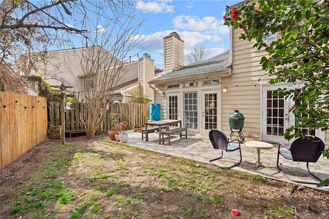 rear view of house featuring a chimney, a patio area, and a fenced backyard