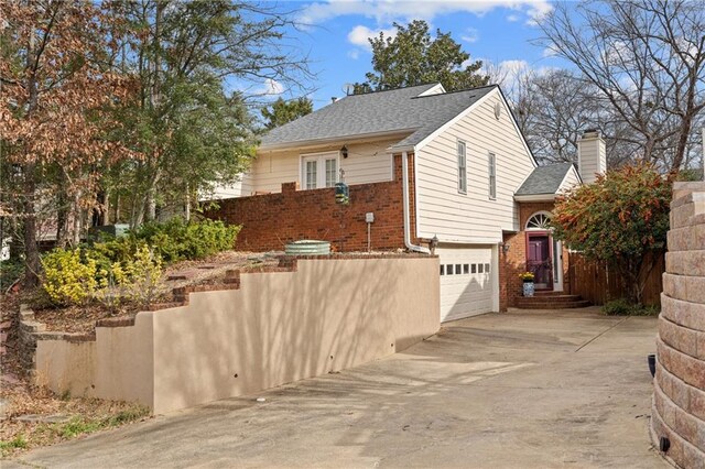 view of side of property with concrete driveway, brick siding, and an attached garage