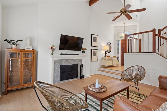 living room featuring a ceiling fan, light wood-type flooring, a fireplace, and stairs