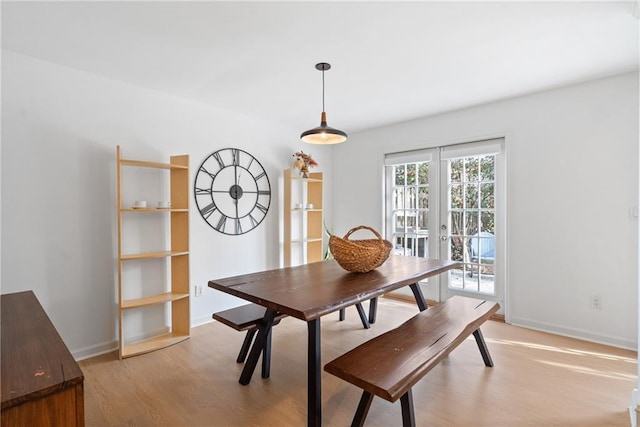 dining space with light wood-type flooring, french doors, and baseboards