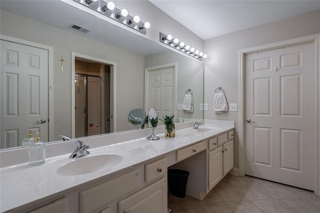 bathroom with a sink, visible vents, double vanity, and tile patterned flooring