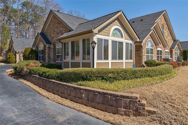 view of home's exterior featuring stone siding and a shingled roof