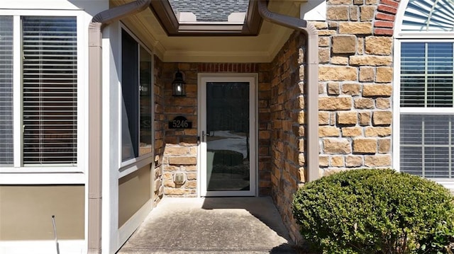 property entrance with stone siding and roof with shingles