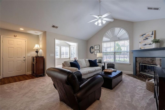 carpeted living room with lofted ceiling, a fireplace, visible vents, and ceiling fan