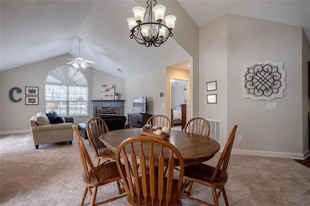 dining area featuring lofted ceiling, carpet, a fireplace, and ceiling fan with notable chandelier