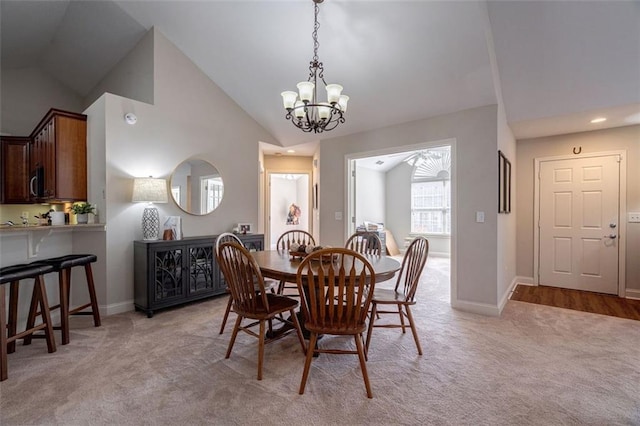 dining room with light carpet, baseboards, high vaulted ceiling, and an inviting chandelier