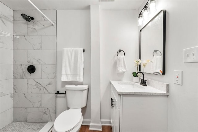 bathroom with vanity, toilet, and tiled shower