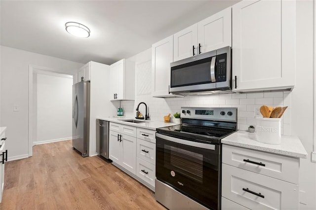 kitchen featuring light wood-type flooring, tasteful backsplash, stainless steel appliances, sink, and white cabinets