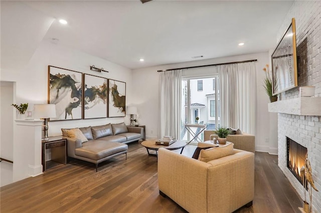 living room featuring a brick fireplace and dark hardwood / wood-style floors