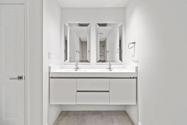 bathroom featuring a sink, baseboards, and double vanity