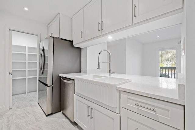 kitchen featuring light stone countertops, recessed lighting, appliances with stainless steel finishes, white cabinets, and a sink