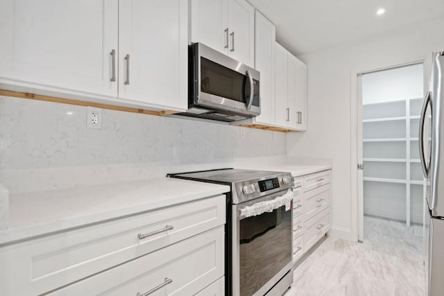 kitchen with recessed lighting, white cabinets, appliances with stainless steel finishes, marble finish floor, and backsplash