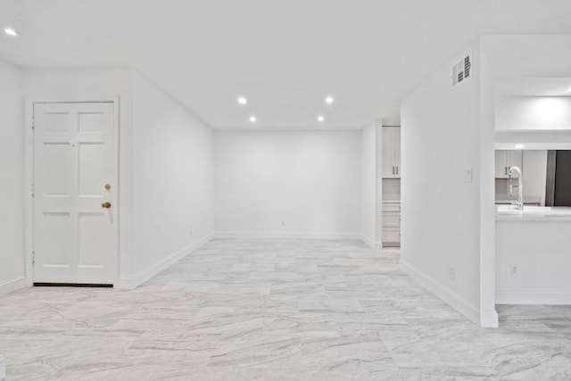 below grade area featuring baseboards, visible vents, recessed lighting, a sink, and marble finish floor