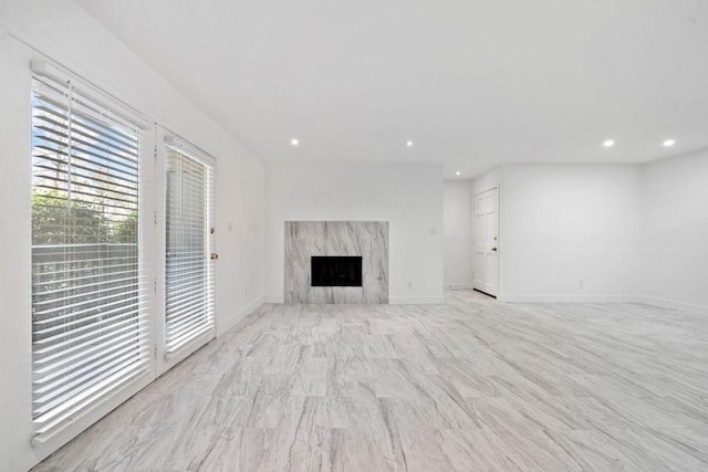 unfurnished living room with recessed lighting, baseboards, and a high end fireplace