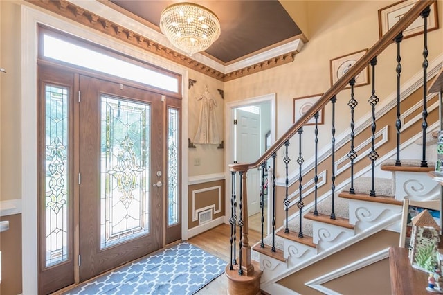 foyer featuring light hardwood / wood-style floors, a notable chandelier, and crown molding