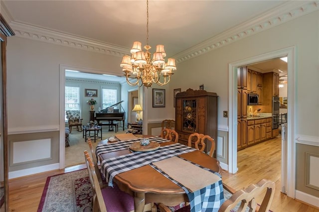 dining space featuring crown molding, light hardwood / wood-style flooring, and an inviting chandelier