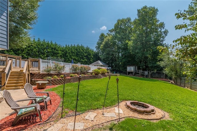 view of yard featuring a deck and an outdoor fire pit