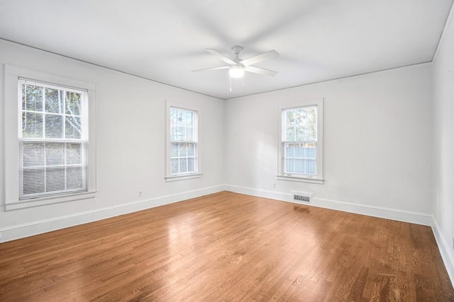 empty room featuring ceiling fan, a healthy amount of sunlight, and wood-type flooring