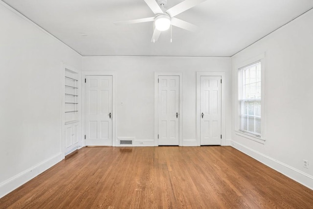 unfurnished bedroom featuring ceiling fan, multiple closets, and light hardwood / wood-style flooring