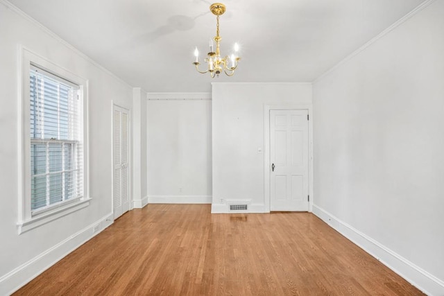 unfurnished room with crown molding, light hardwood / wood-style flooring, and a chandelier