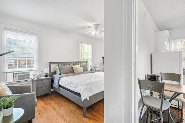 bedroom featuring ceiling fan, cooling unit, and light wood-type flooring