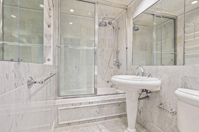 bathroom featuring shower / bath combination with glass door, tile walls, and toilet