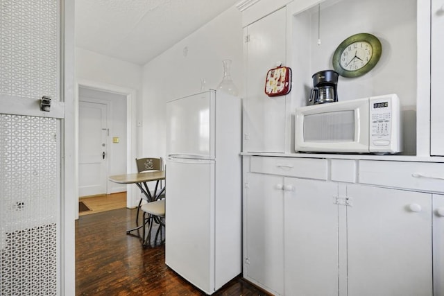 kitchen with white cabinetry, dark hardwood / wood-style flooring, and white appliances