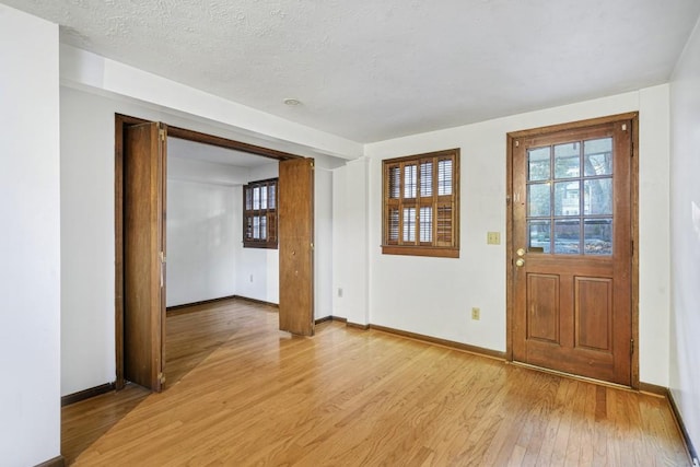 foyer entrance with a textured ceiling and light wood-type flooring