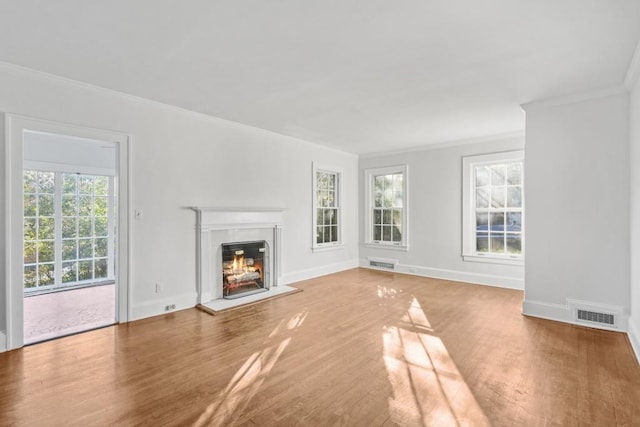 unfurnished living room with hardwood / wood-style floors, a healthy amount of sunlight, and crown molding