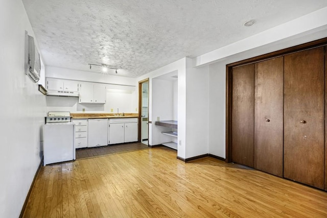 kitchen featuring white appliances, white cabinets, sink, a textured ceiling, and light hardwood / wood-style floors