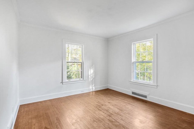 spare room with hardwood / wood-style flooring, crown molding, and a healthy amount of sunlight