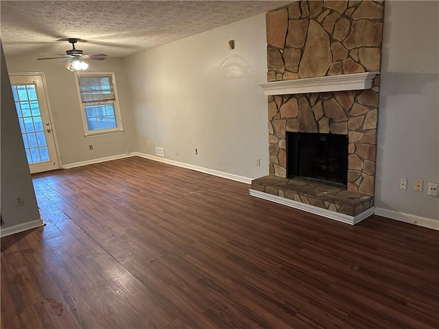 unfurnished living room featuring ceiling fan, a fireplace, dark hardwood / wood-style flooring, and a textured ceiling