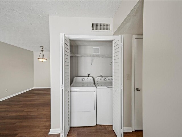 clothes washing area with dark hardwood / wood-style flooring, a textured ceiling, and independent washer and dryer