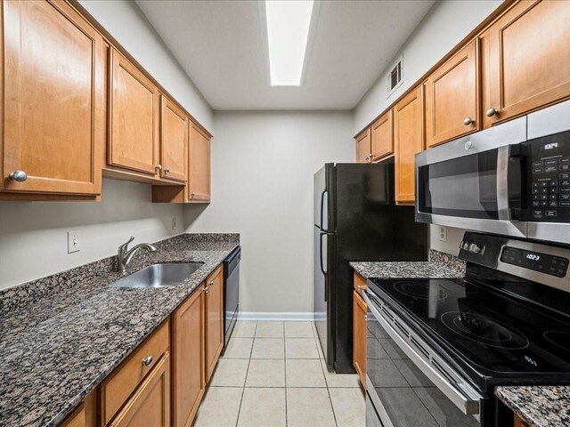 kitchen featuring light tile patterned flooring, dark stone countertops, sink, and appliances with stainless steel finishes