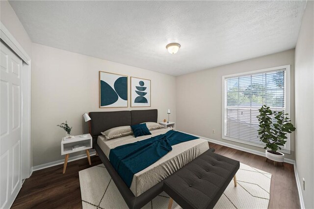 bedroom with a textured ceiling, dark hardwood / wood-style floors, and a closet